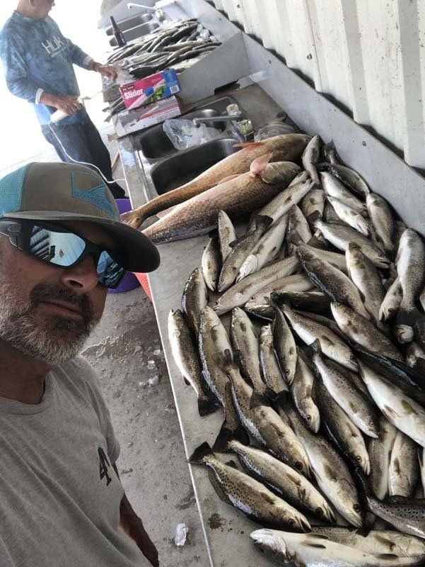 A man is standing in front of a table filled with fish.
