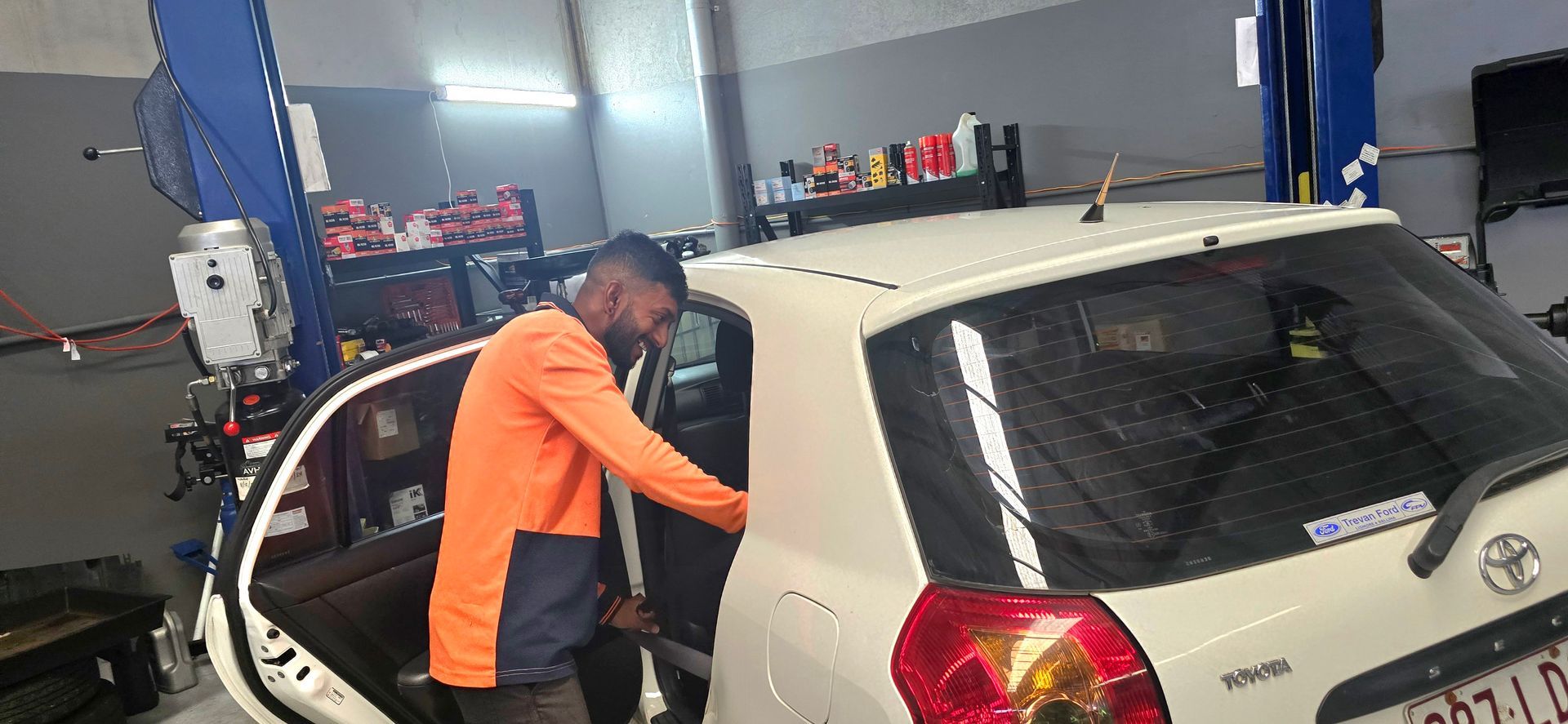 a Mechanic in an Orange Shirt Working on a White Car Inside a Garage — QA Oxley in Oxley, QLD