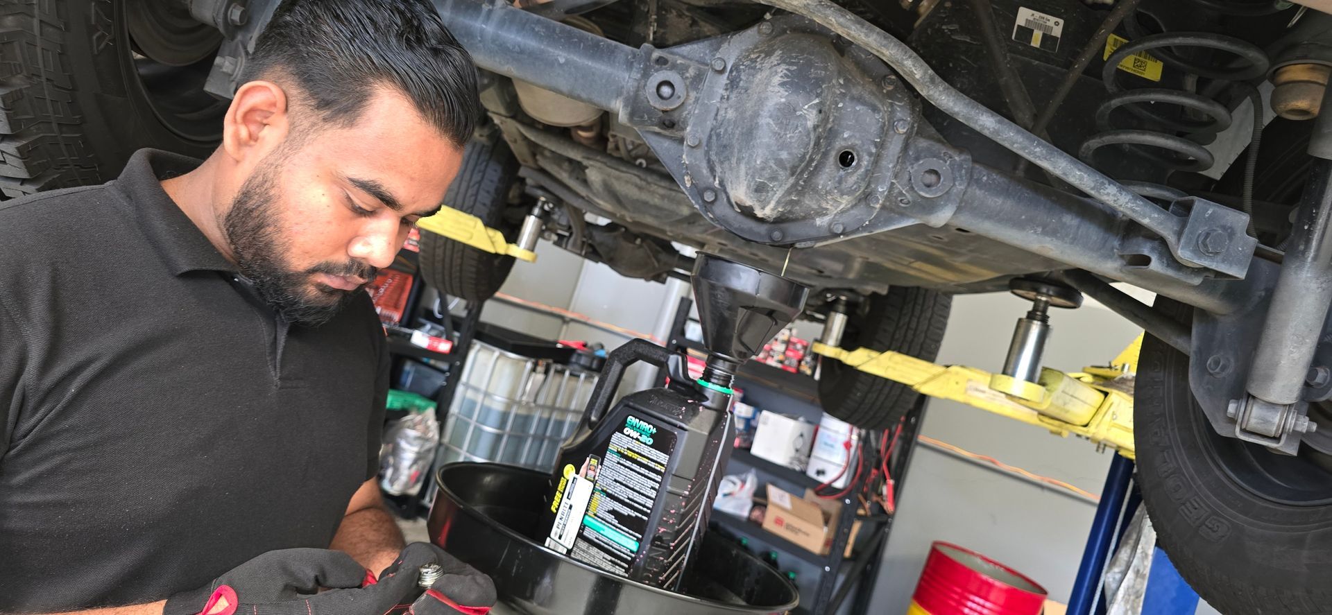 a Mechanic is Working Under a Raised Vehicle, Changing the Oil in a Shop — QA Oxley in Sherwood, QLD