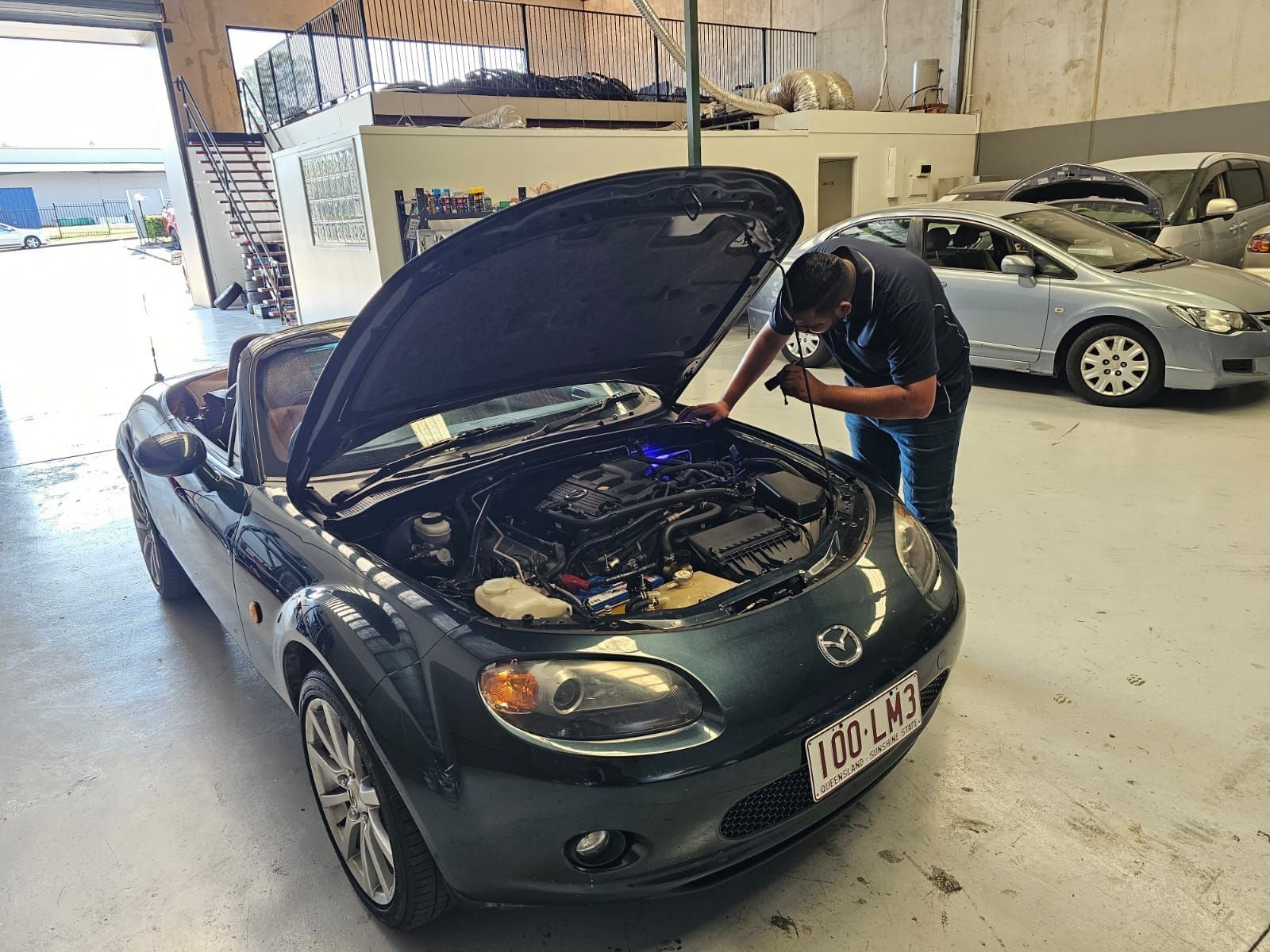 Mechanic Inspecting the Engine of a Green Mazda Miata in a Garage — QA Oxley in Oxley, QLD