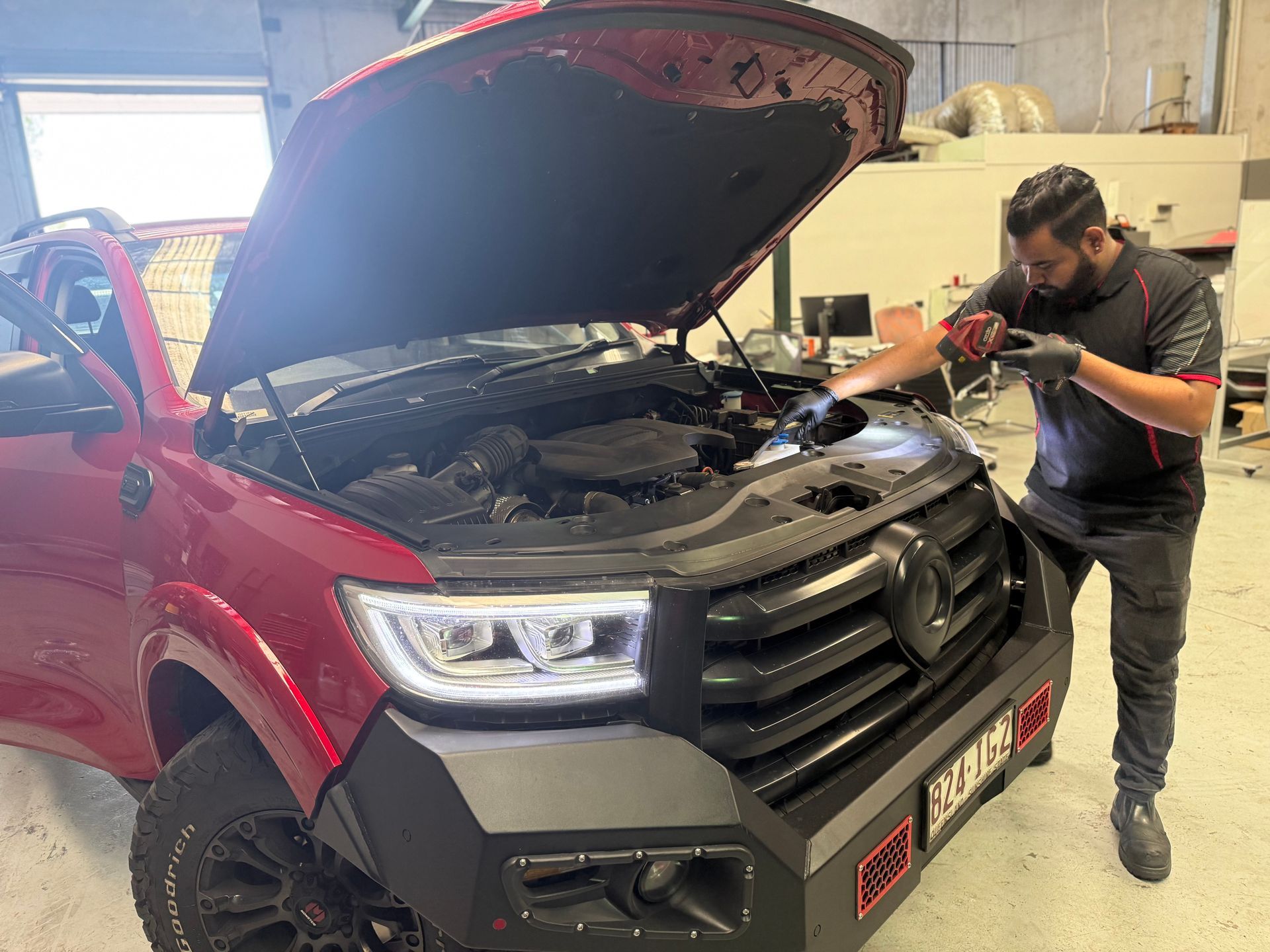 Mechanic in Blue Coveralls Checks a Car Engine, Writing on a Clipboard With a Pencil — QA Oxley in Oxley, QLD