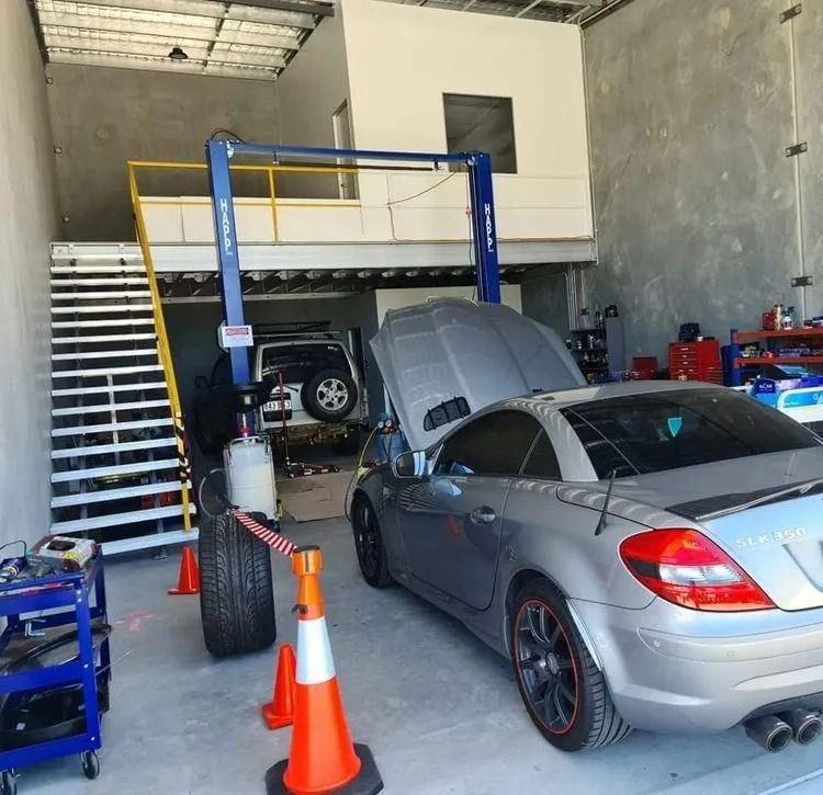 A Car Repair Shop With a Car on a Lift, a Silver Car, and a Staircase to a Mezzanine — QA Oxley in Oxley, QLD