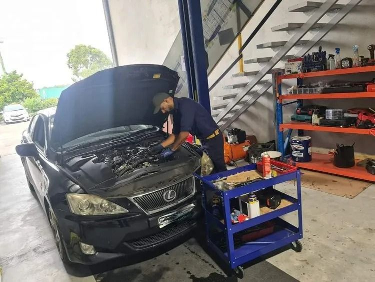 Mechanic Working on a Black Car Engine in a Garage; a Tool Cart is Nearby — QA Oxley in Oxley, QLD