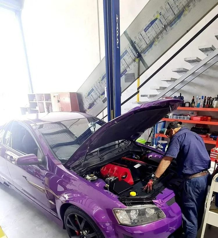 Mechanic Working on a Purple Car With Its Hood Open in a Garage — QA Oxley in Darra, QLD