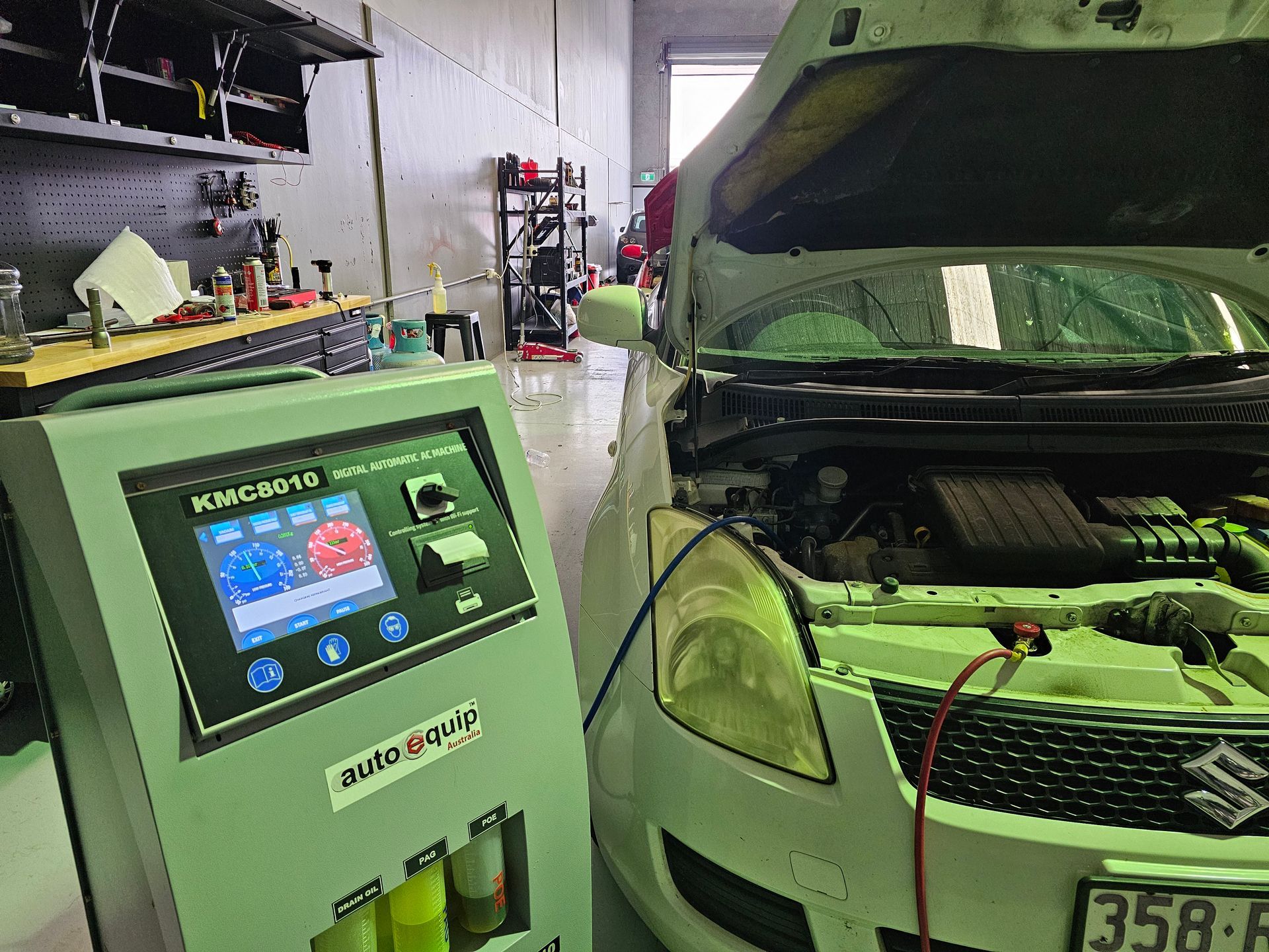 a White Suzuki Swift With Its Hood Open, Connected to an Auto Maintenance Machine in a Workshop — QA Oxley in Oxley, QLD