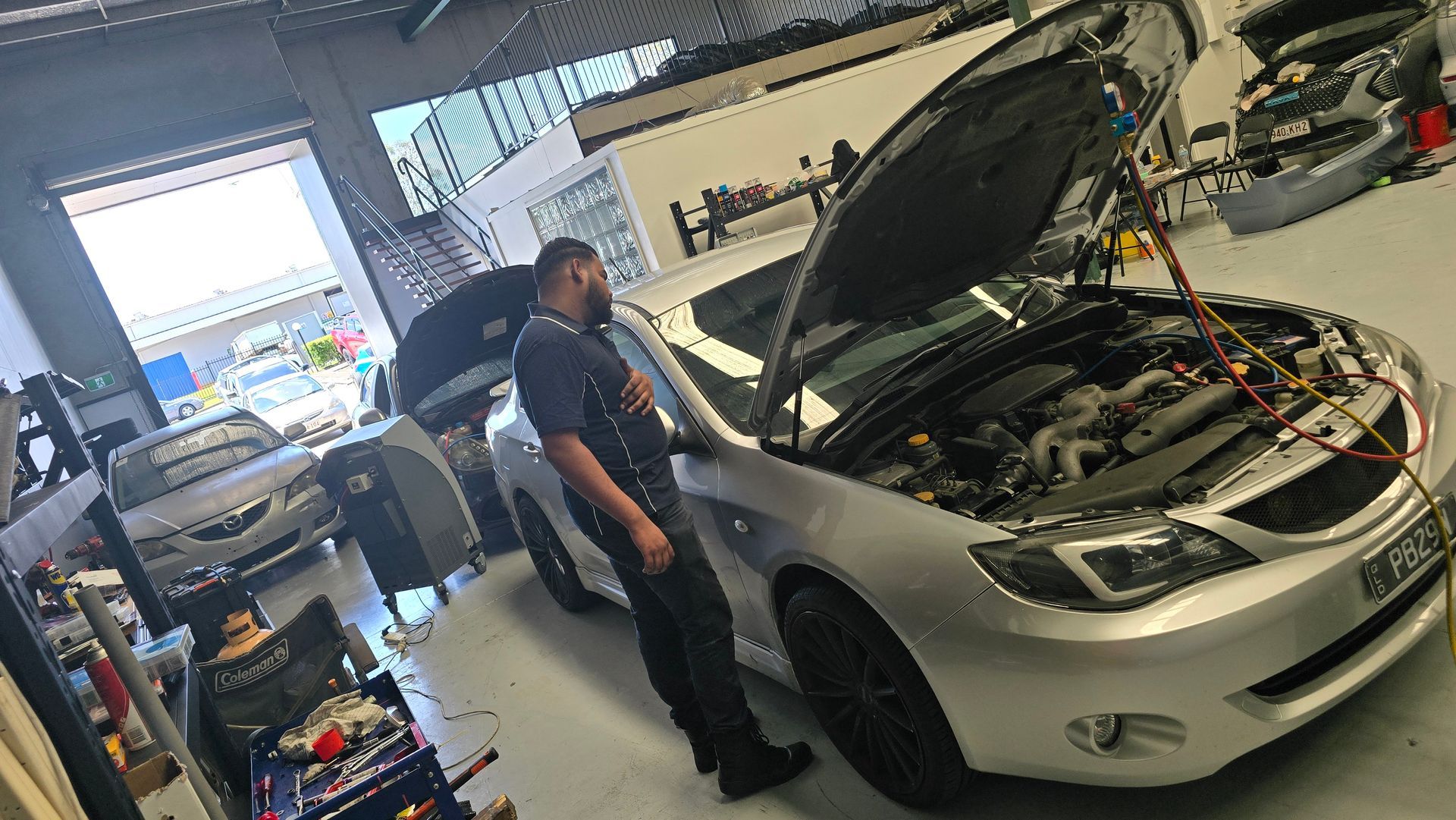 A Mechanic Working on a Silver Car With an Open Hood in a Garage — QA Oxley in Oxley, QLD