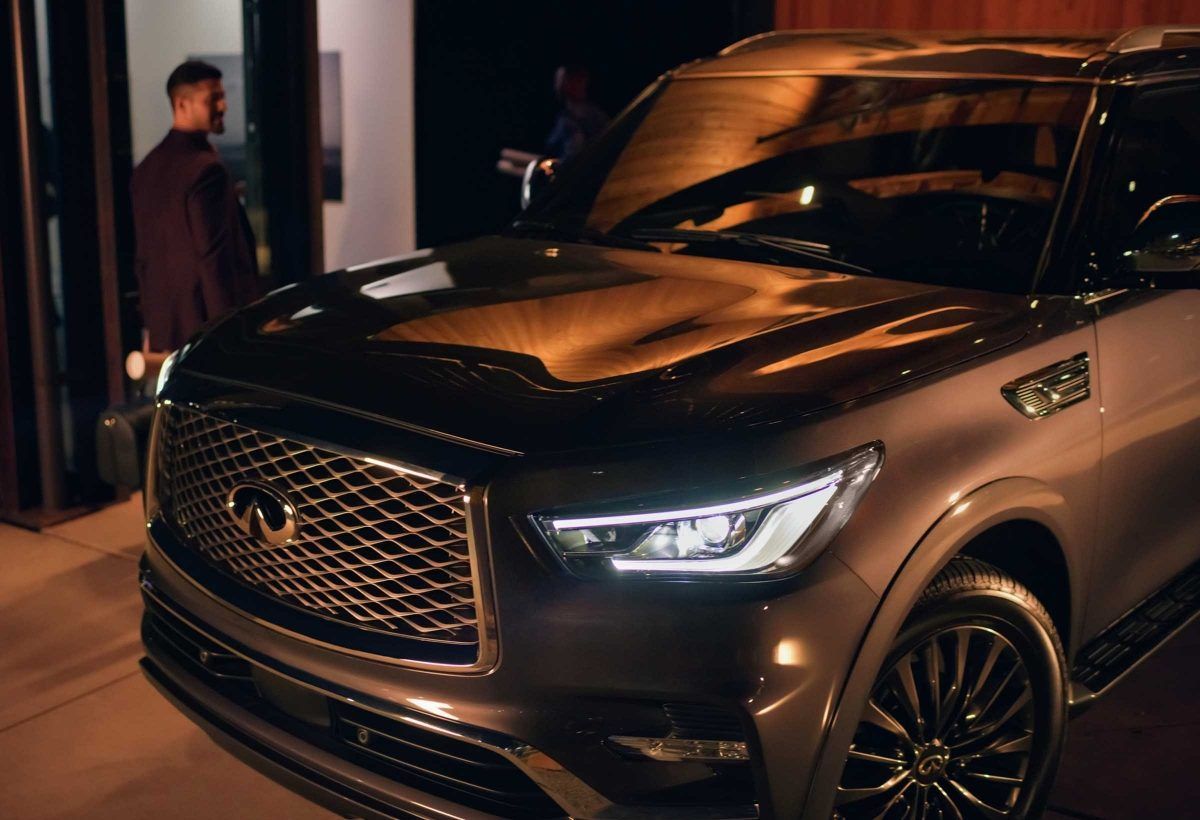 A man is standing in front of a black infiniti qx80 suv.