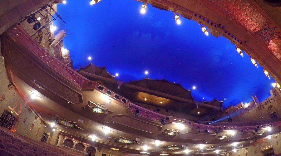 Looking up at the ceiling of an auditorium with a blue sky in the background.