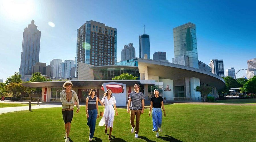 A group of people are walking in a park in front of a city skyline.