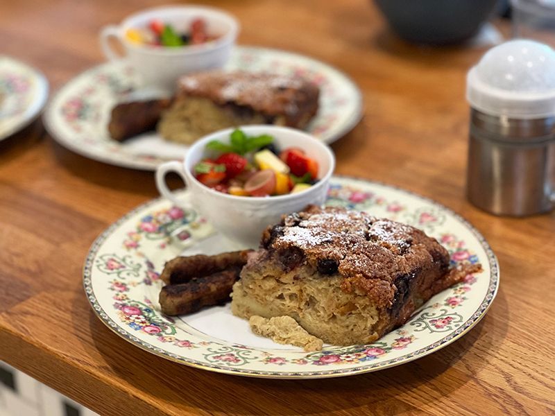 A plate of food with a cup of fruit salad on a wooden table.