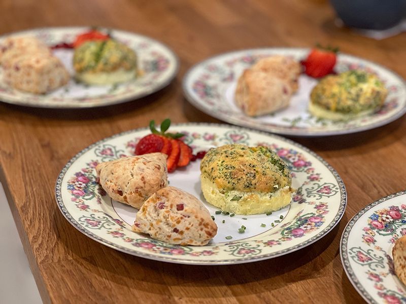 Four plates of food with strawberries on them are on a wooden table.