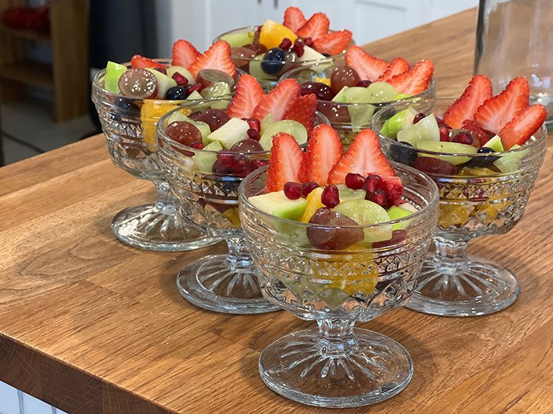 Three bowls of fruit salad are sitting on a wooden table.