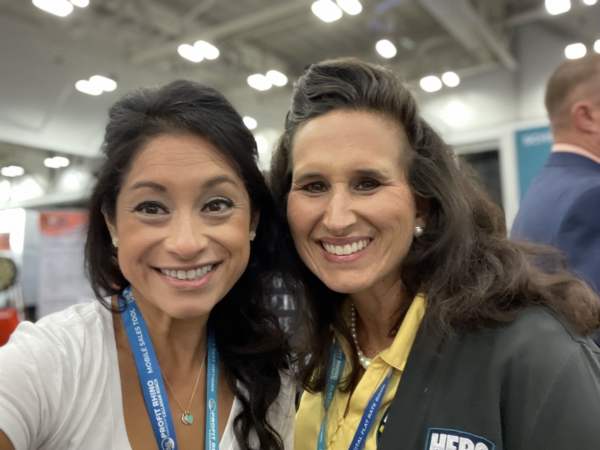 Two women are posing for a picture together at a convention.