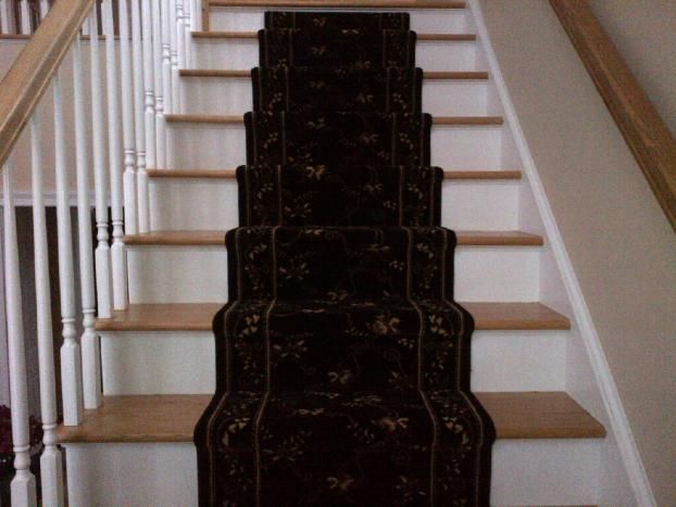 A staircase with a black carpet and white railing