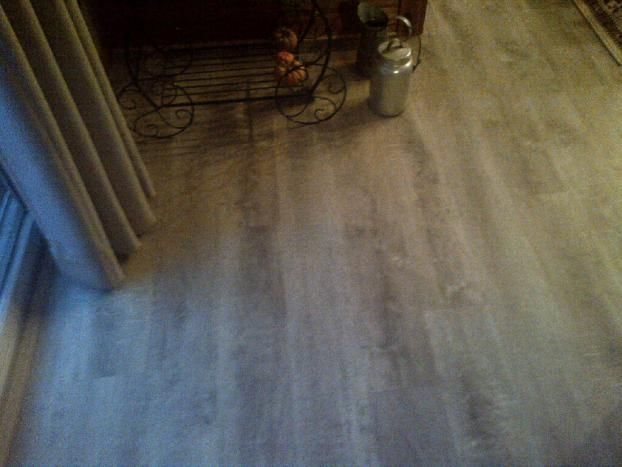 A wooden floor in a living room with a basket of fruit on it.