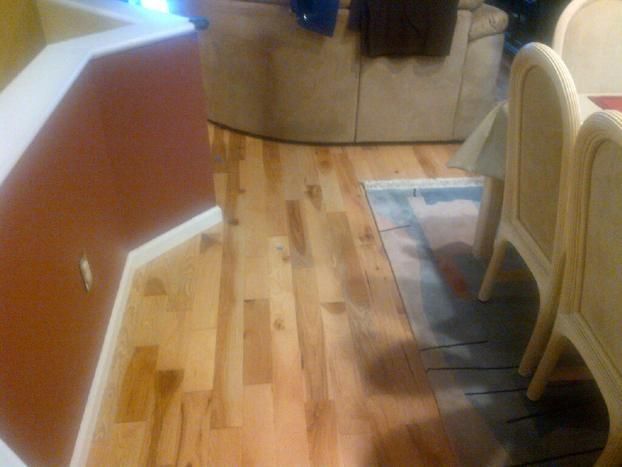 A living room with hardwood floors and wicker chairs