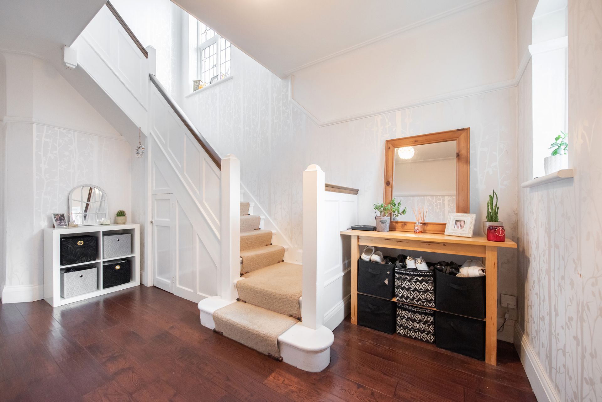 A living room and stairs in a house with wooden beams.