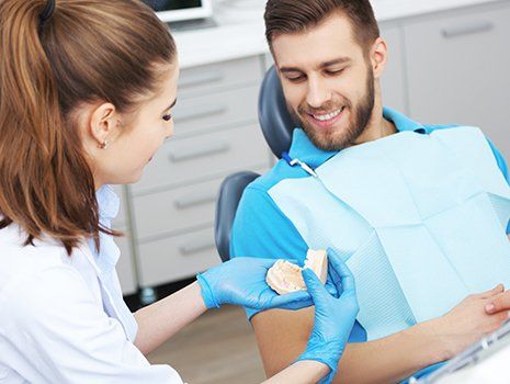 Dentist explaining to patient how to properly brush his teeth in Mililani