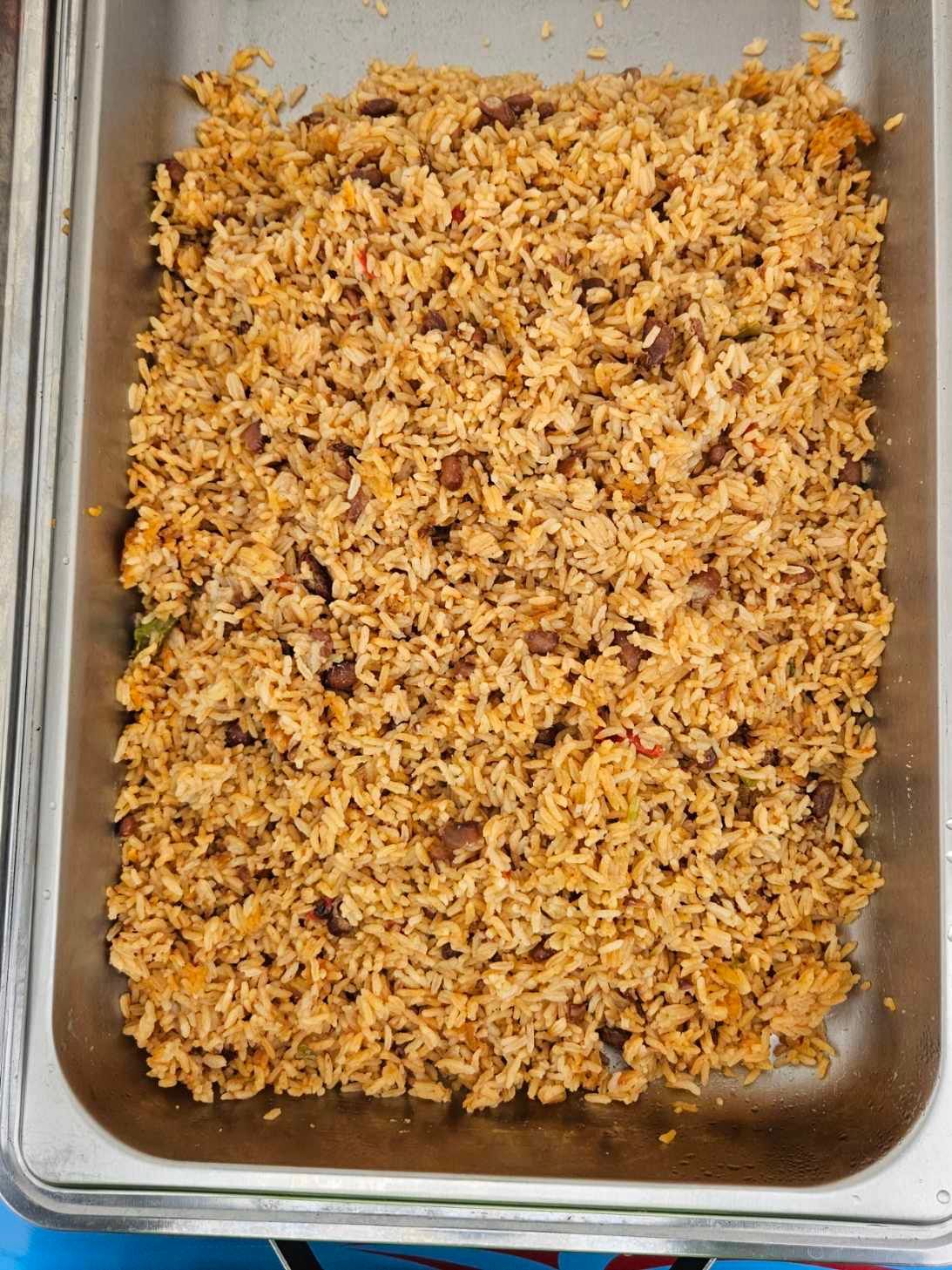 Rice dish in a rectangular stainless steel tray. The rice is a brownish-orange color and appears to have other ingredients mixed in. Prepared for a Wedding.
