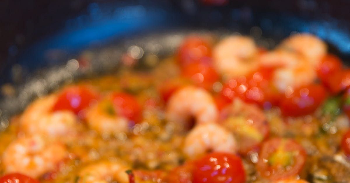 A close up of a pan filled with shrimp and tomatoes.