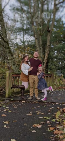 A man , woman and child are posing for a picture in a park.