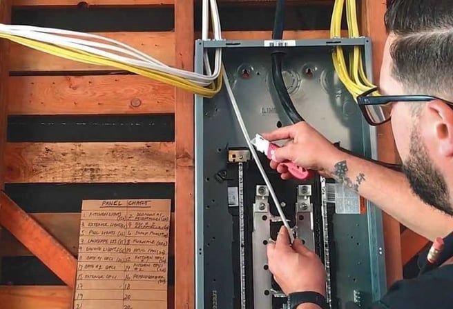 A man is working on an electrical box in a house.