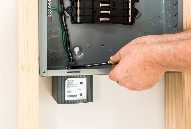 A man is using a screwdriver to fix an electrical box.