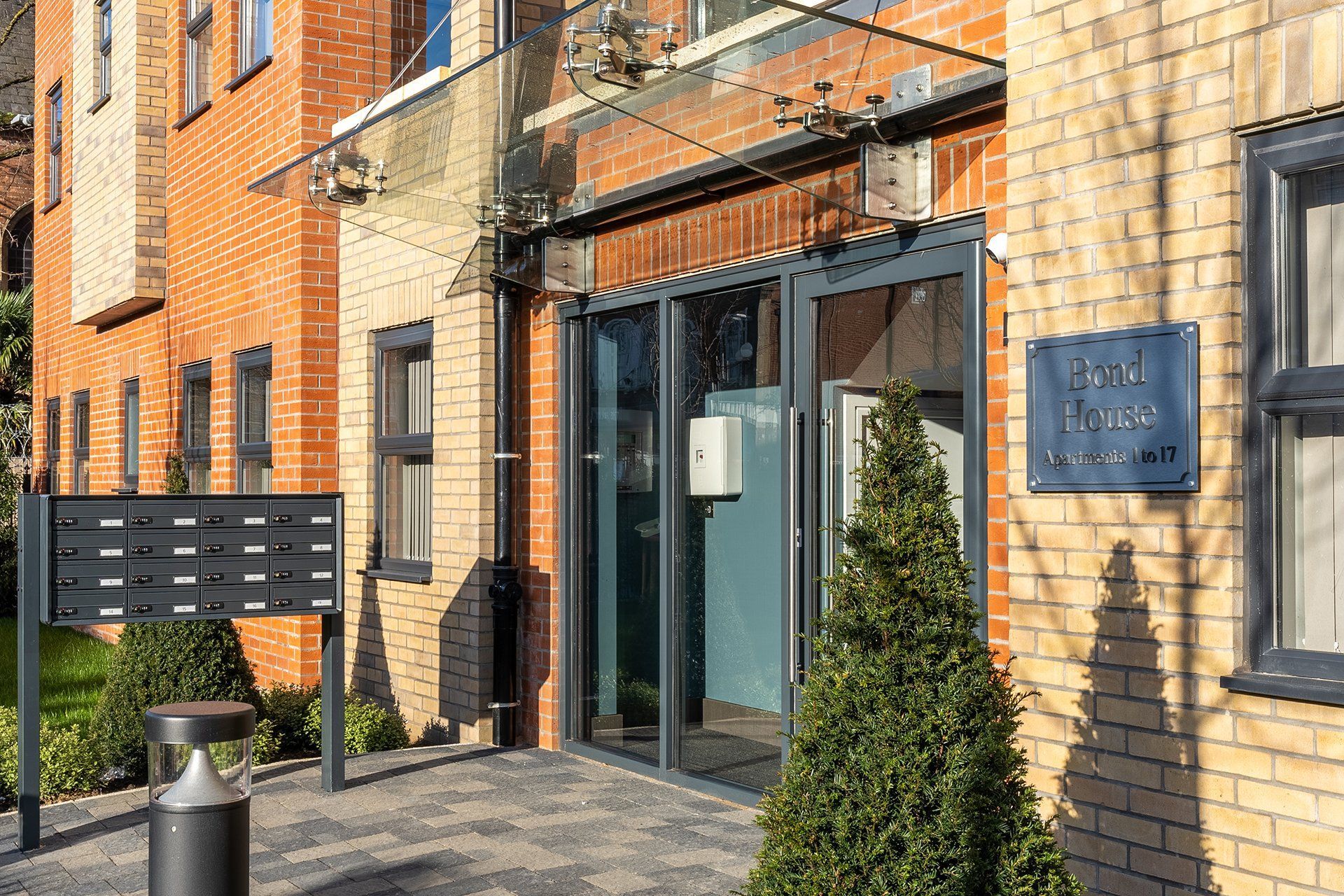 Entrance to Bond House with glass canopy, mailboxes, and a sign reading 