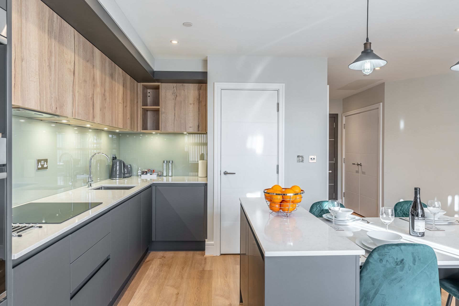 Modern kitchen in a serviced apartment with wood cabinets, island, and a bowl of oranges.