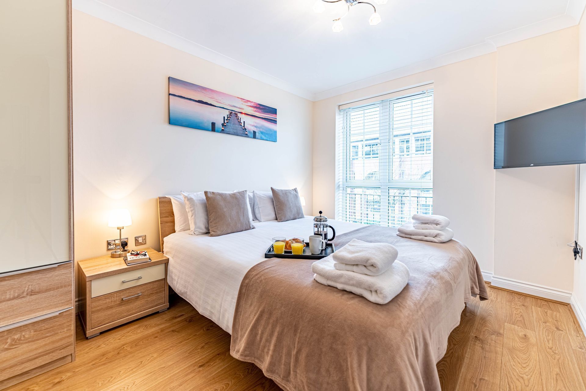 Modern bedroom with a gray headboard, yellow accents, white bedding, and a bedside lamp.