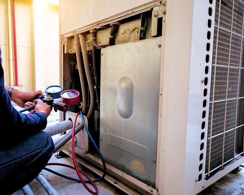 Professional HVAC technician checking refrigerant levels during a seasonal tune-up.