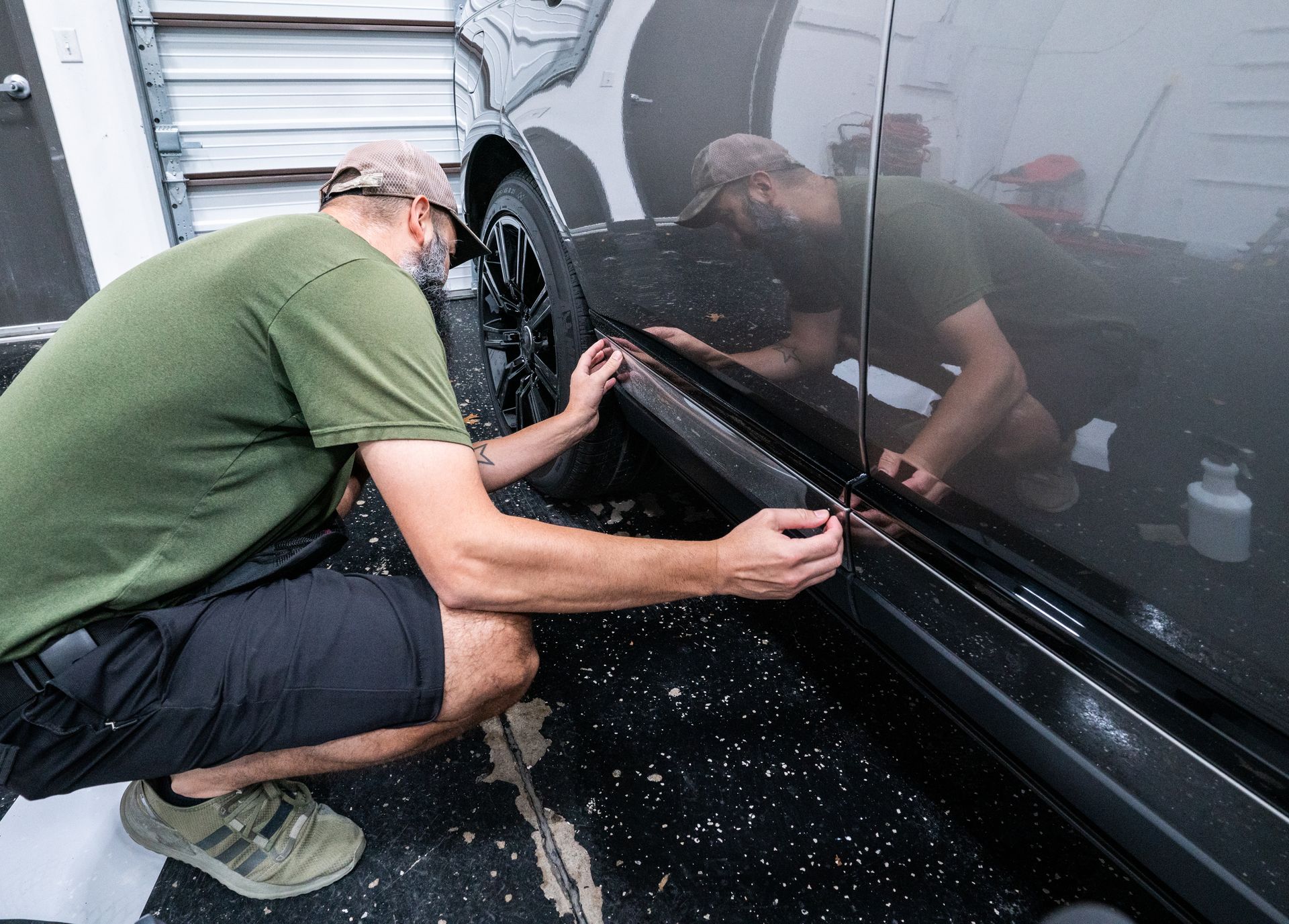 A man is kneeling down in front of a car.