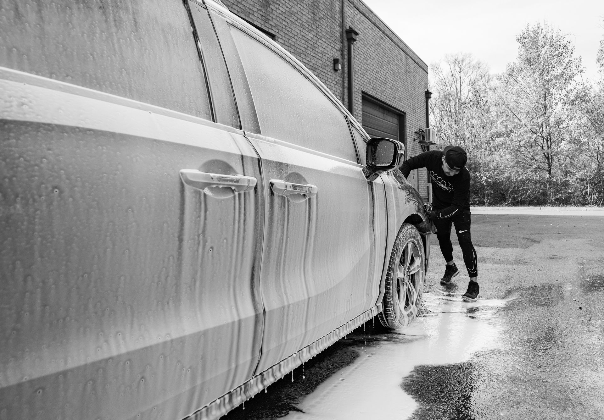 A man is washing a car with foam in a black and white photo.