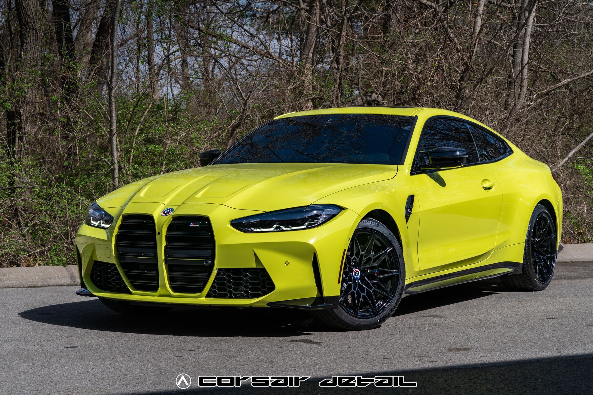 A yellow bmw m4 is parked on the side of the road.