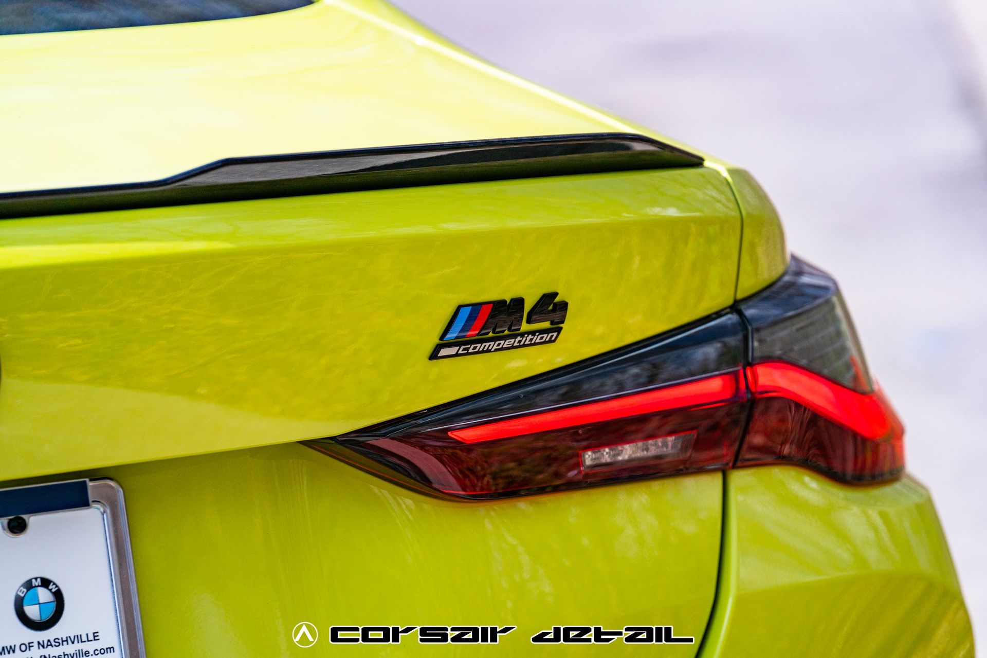 The rear end of a yellow bmw m4 is shown.