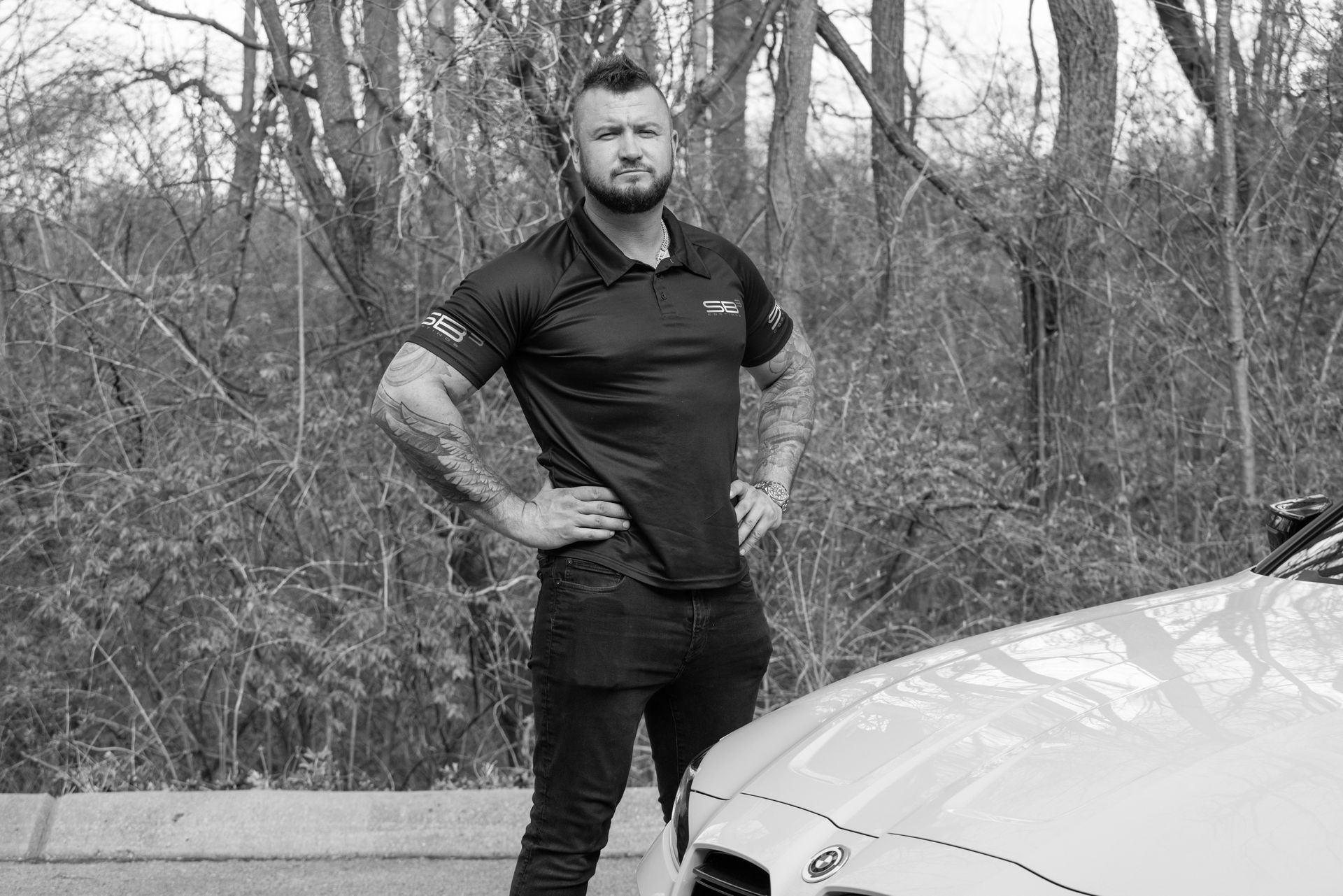 A man is standing next to a car in a black and white photo.
