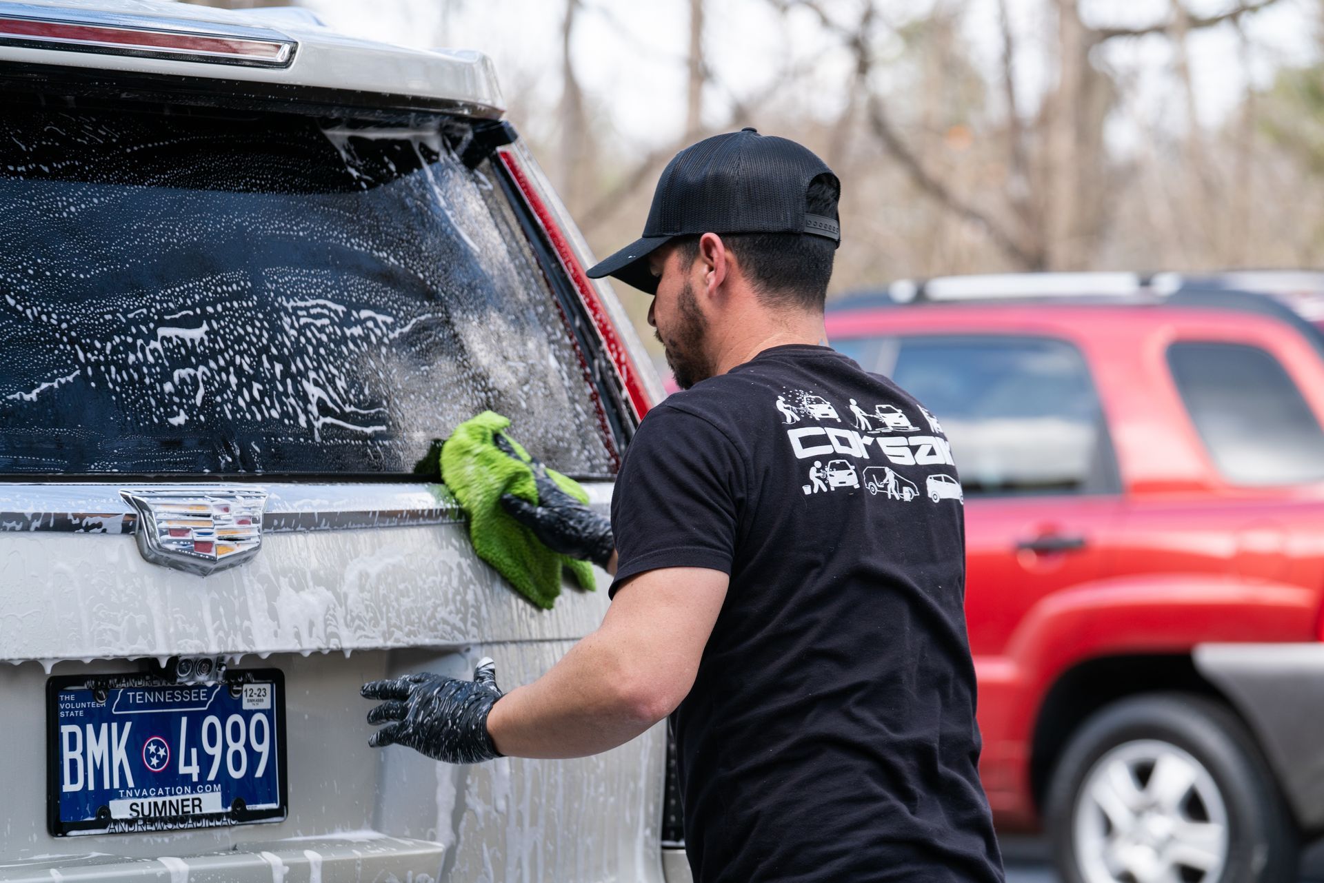 A man is washing a car in a parking lot.