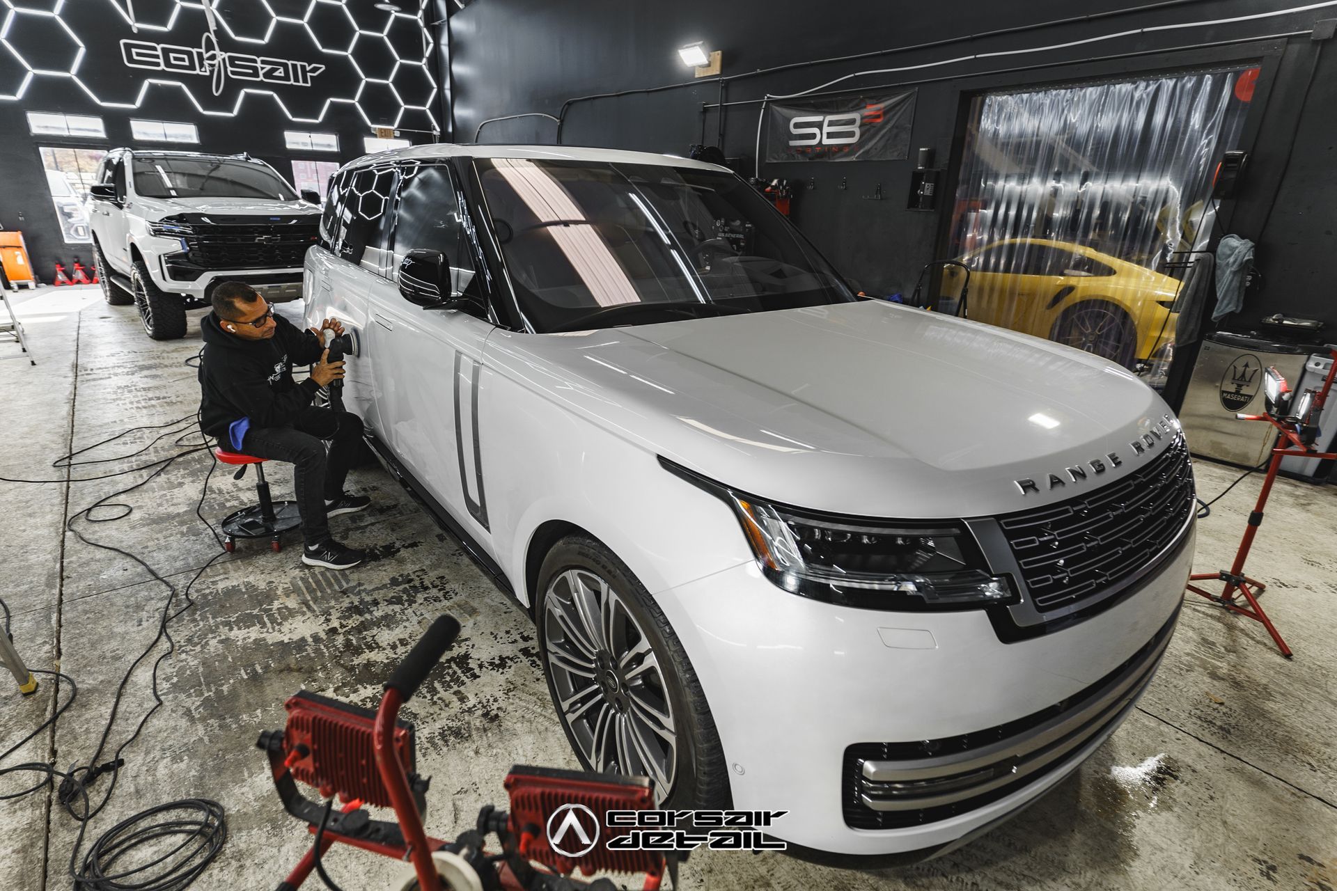 A man is polishing a white range rover in a garage.