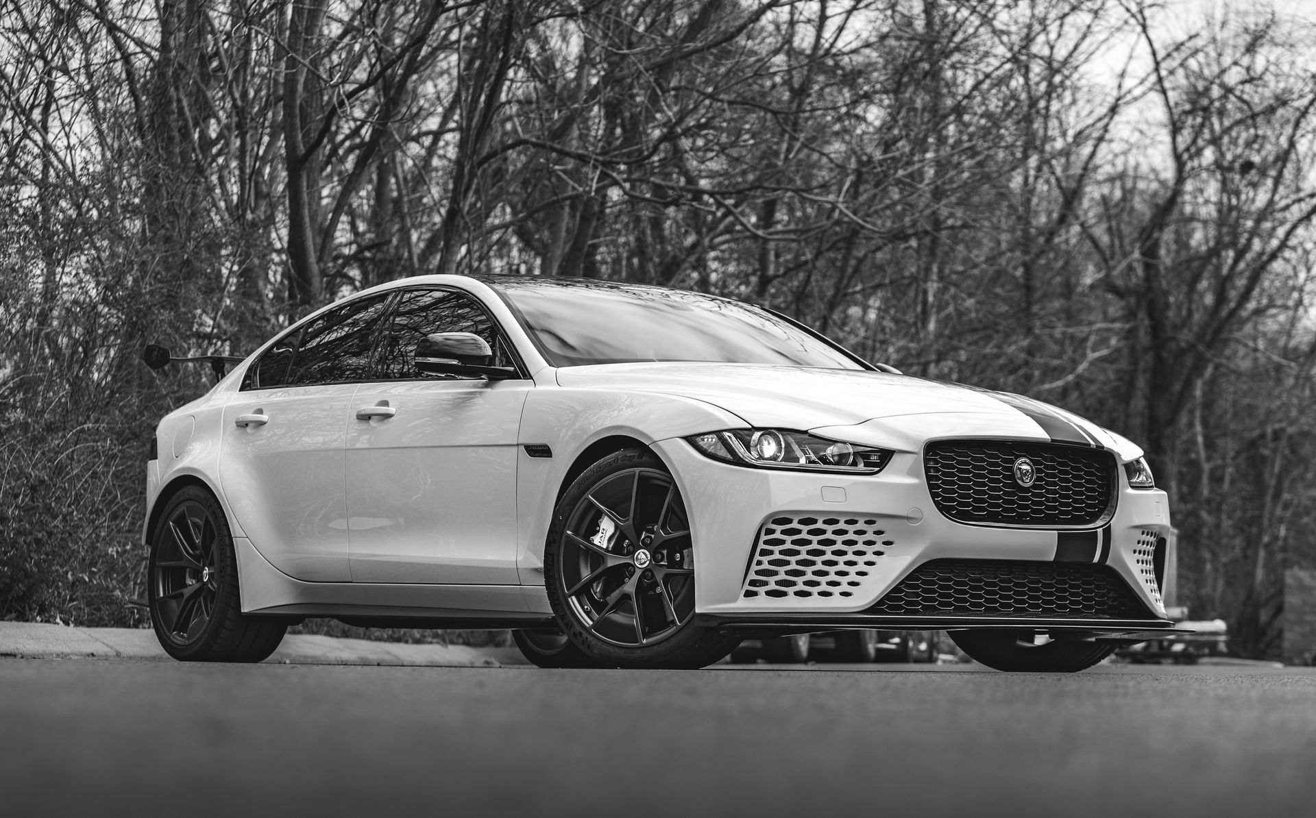 A black and white photo of a white car parked on the side of a road.