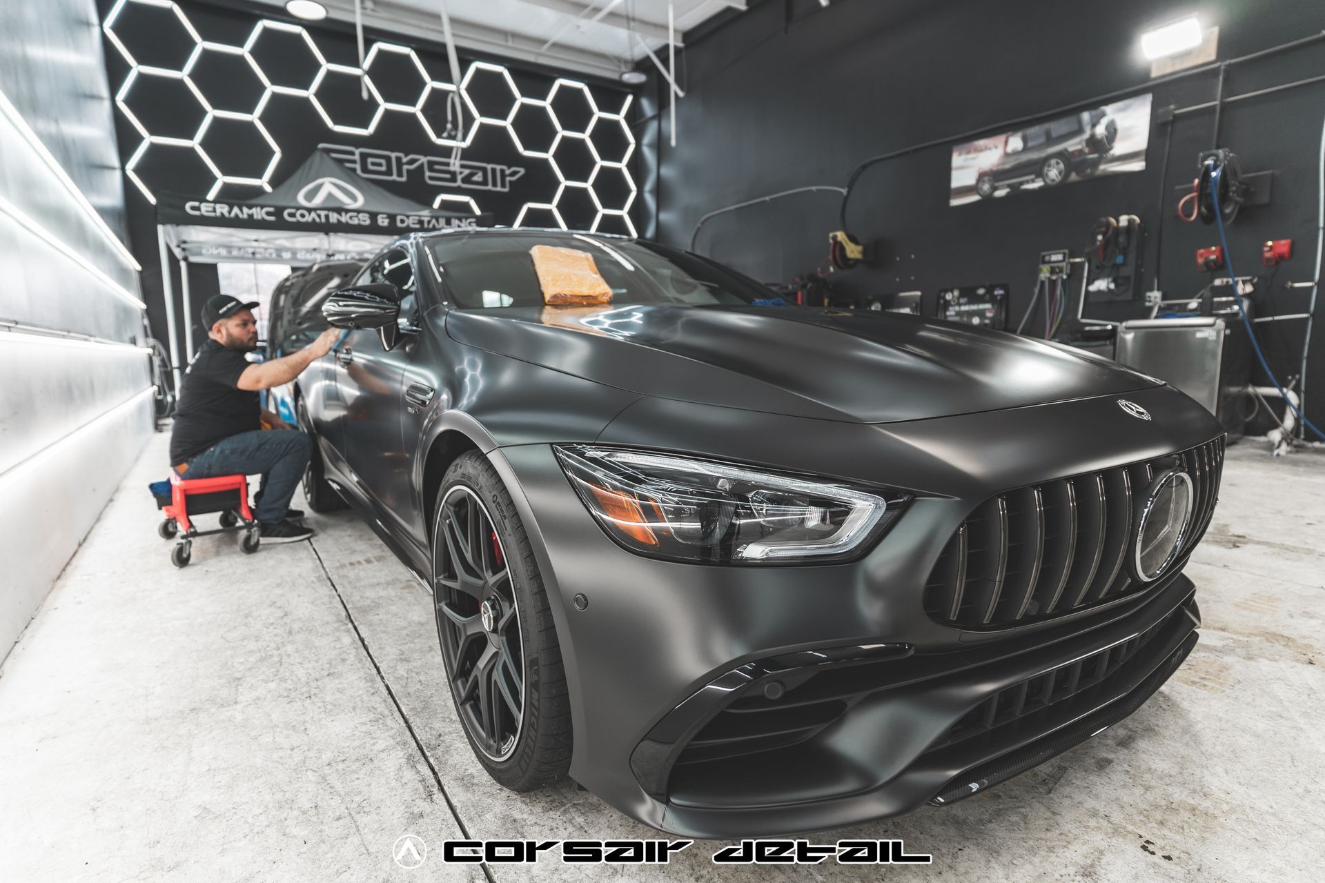A man is working on a black car in a garage.