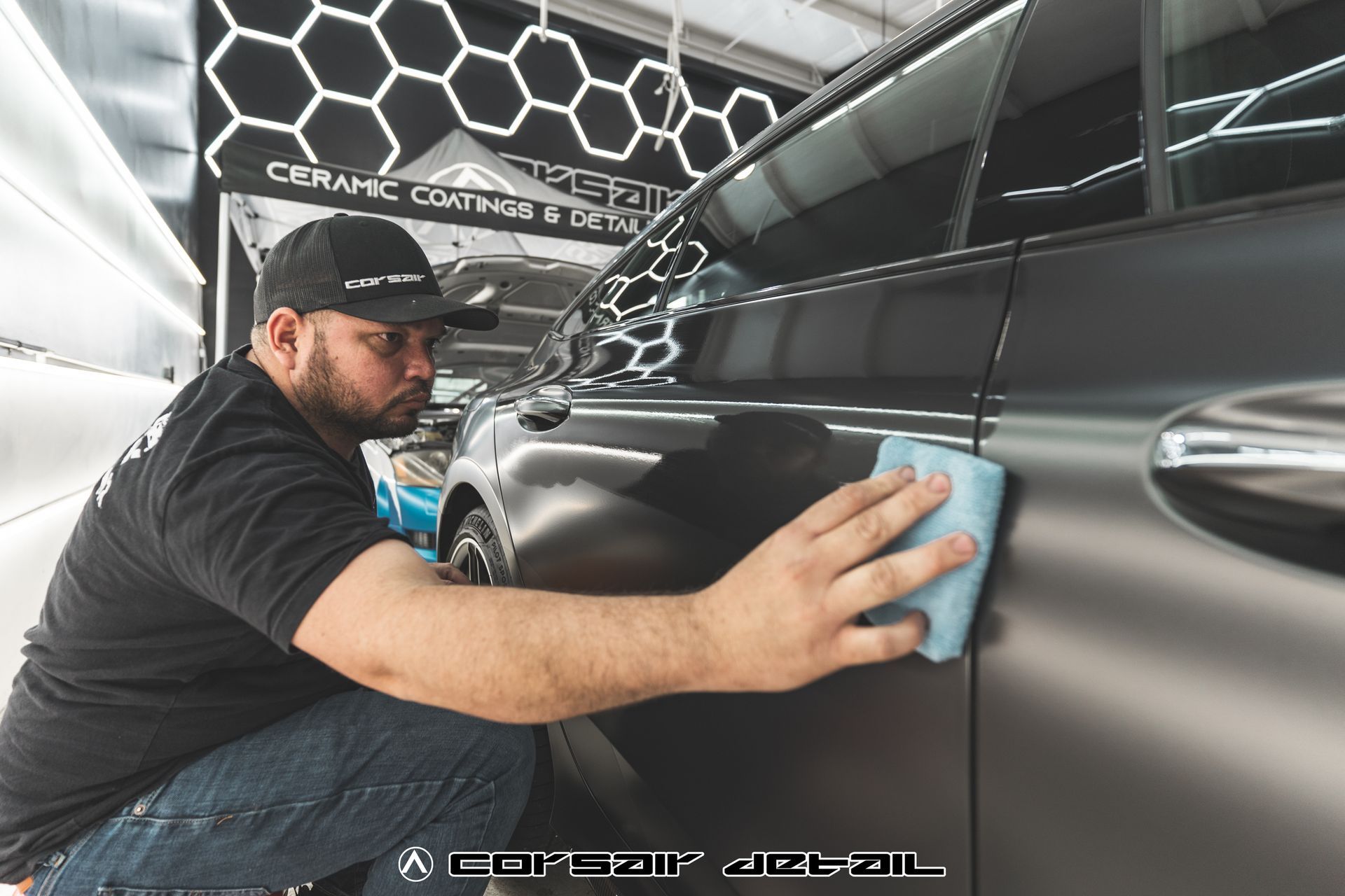 A man is cleaning a black car with a cloth.
