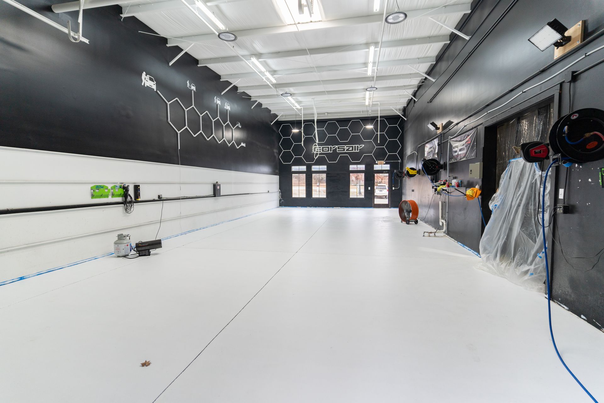 A large empty detailing bay with a white floor and black walls.