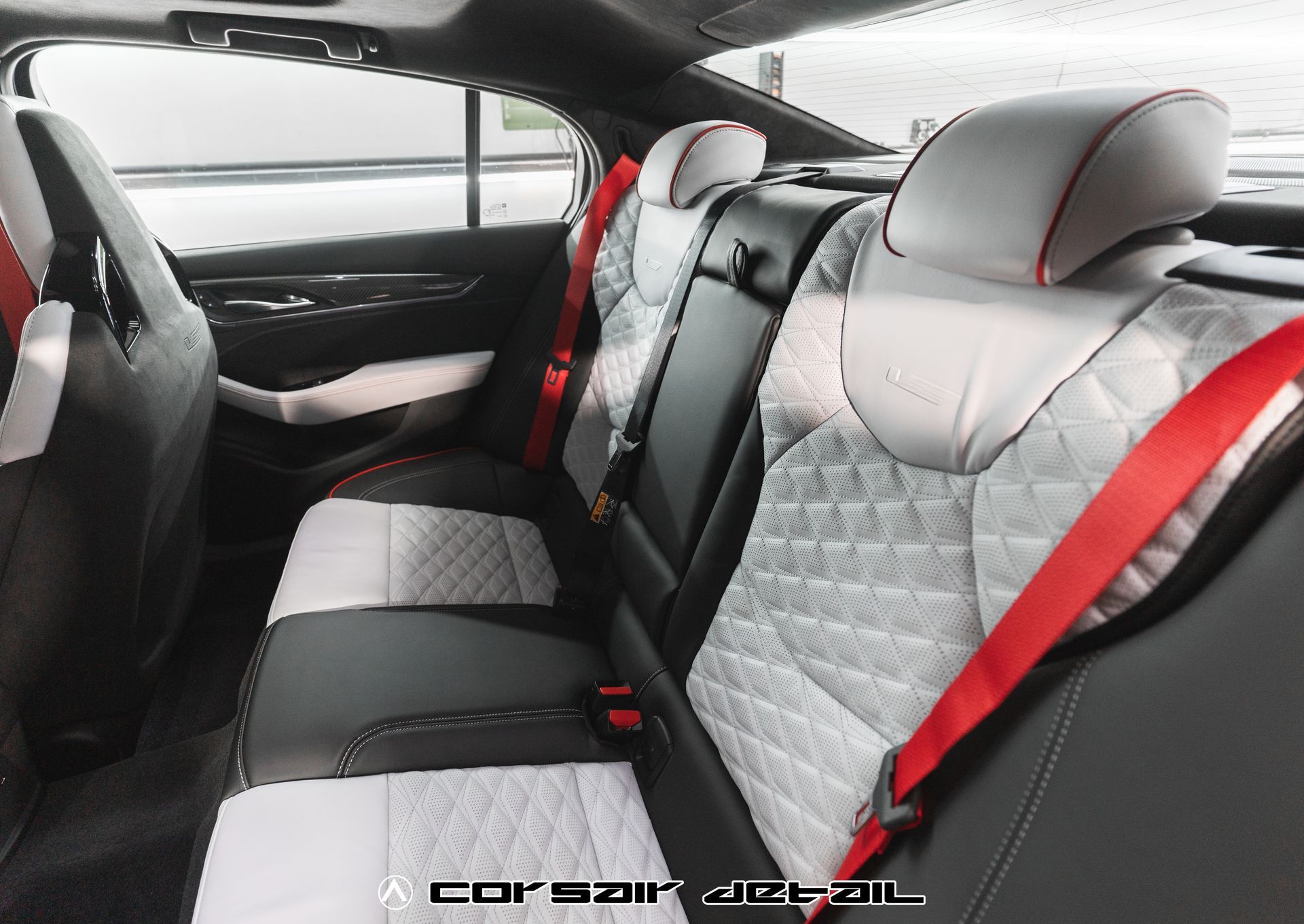 The back seat of a car with red seat belts