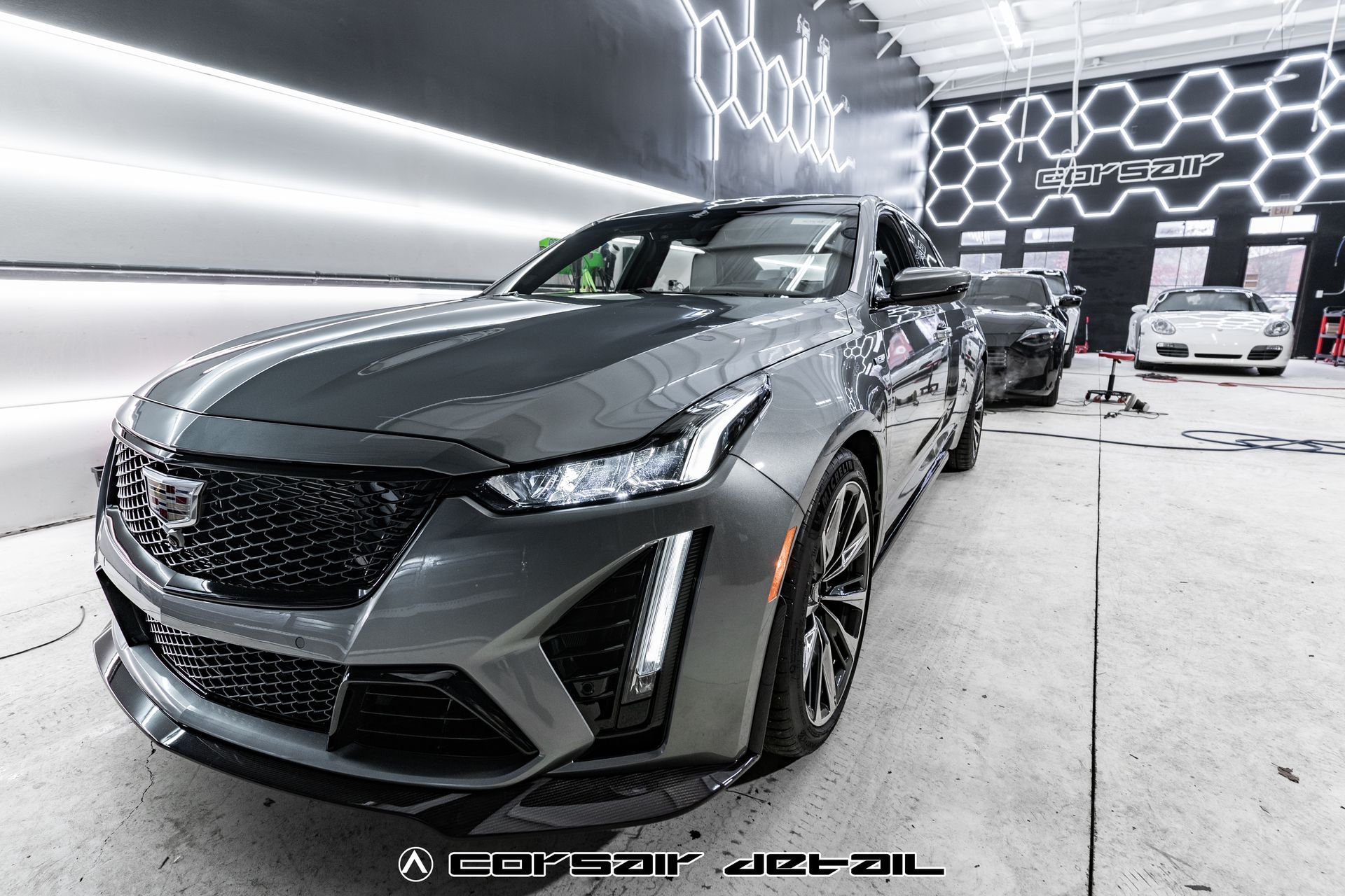 A gray car is parked in a garage with other cars.