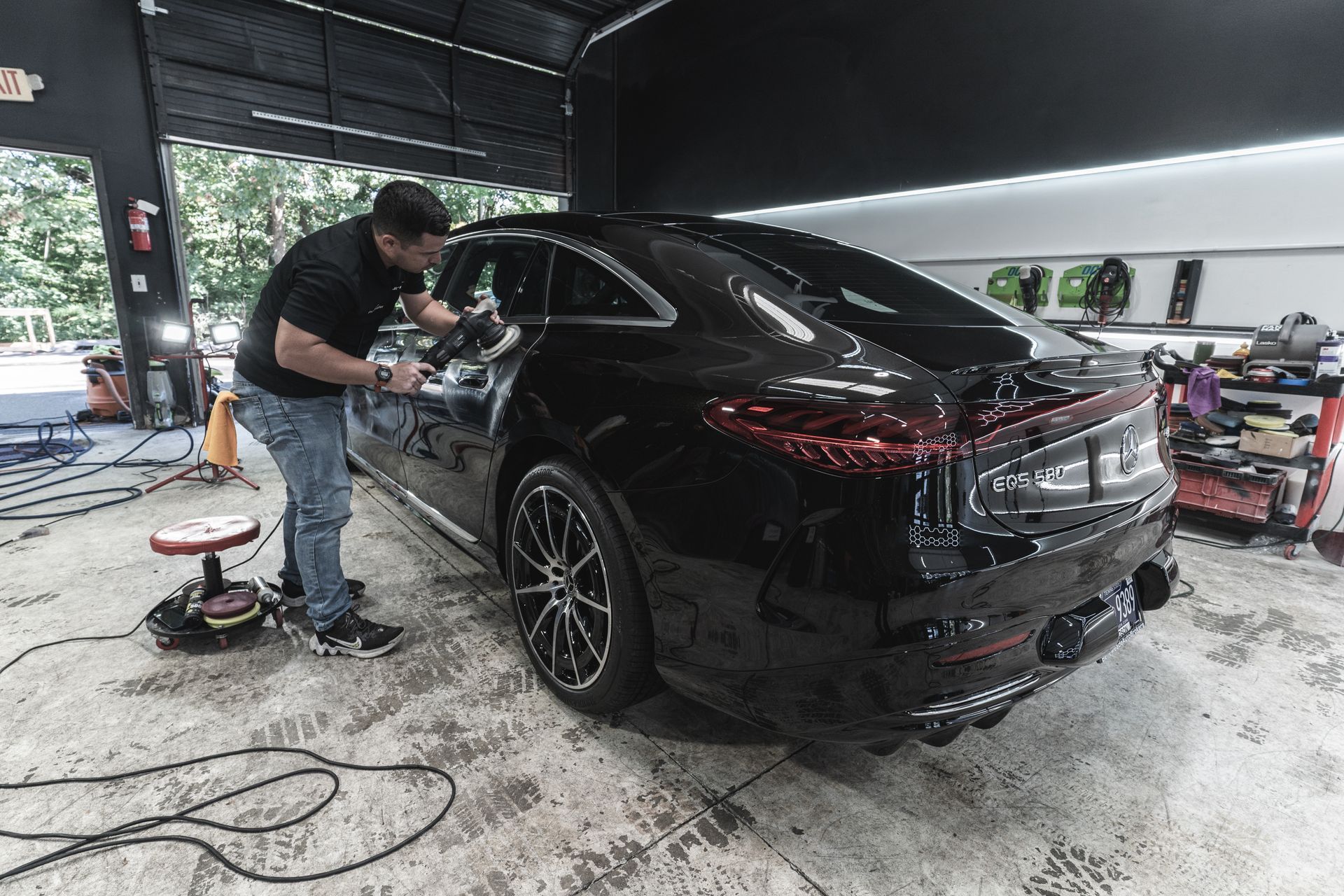 A man is polishing a black car in a garage.
