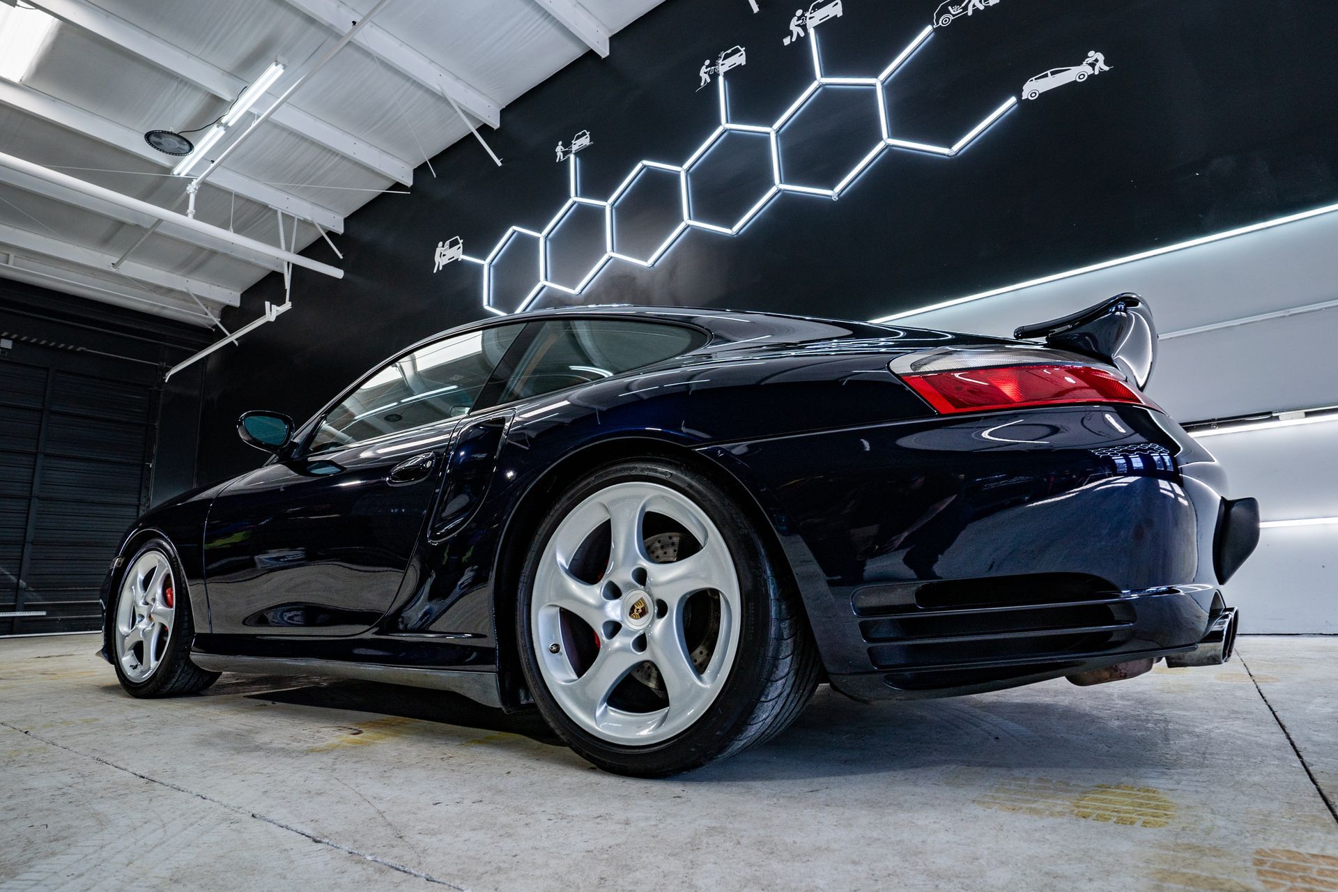 A black porsche 911 turbo is parked in a garage.