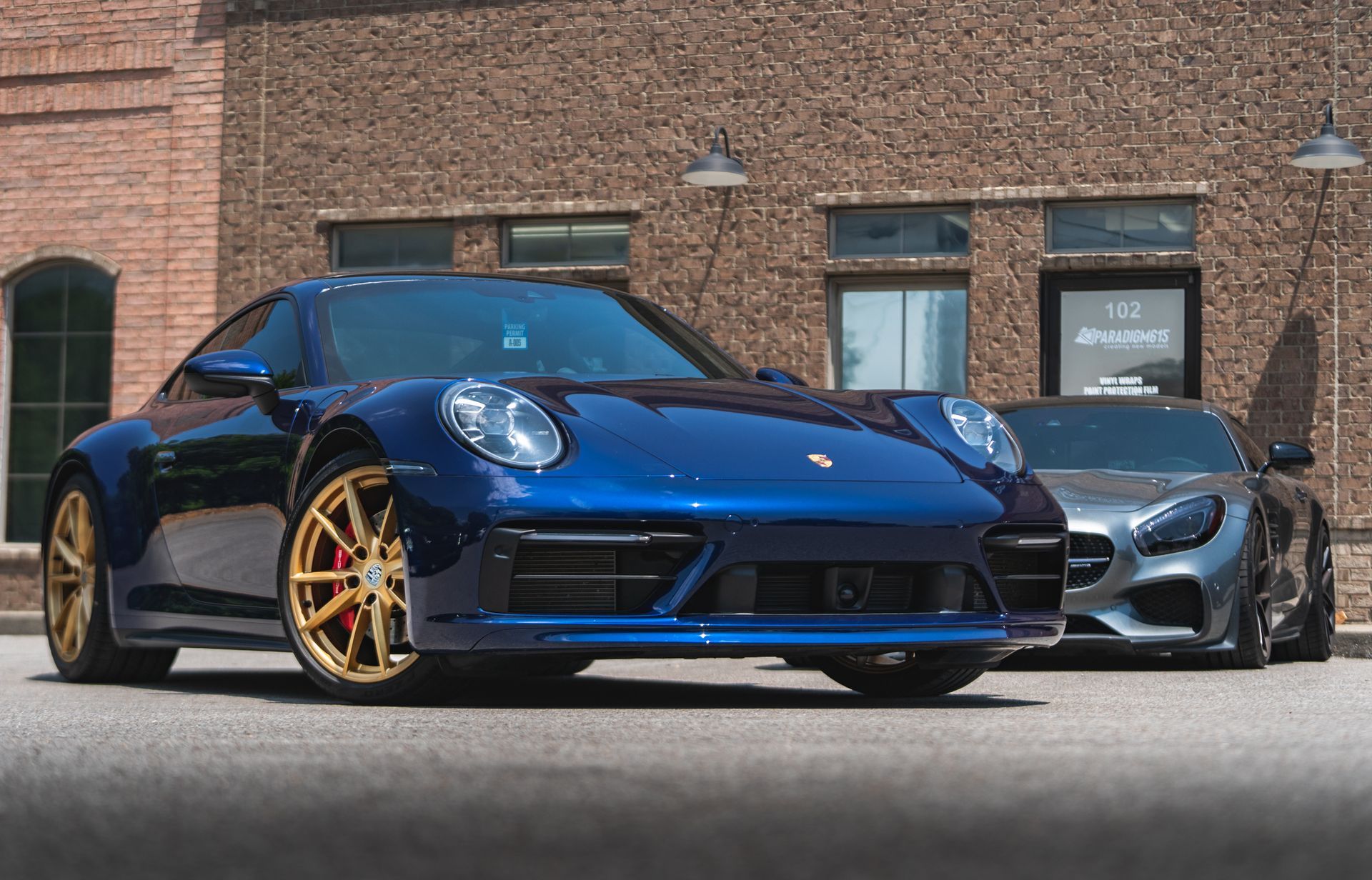Two sports cars are parked in front of a brick building.