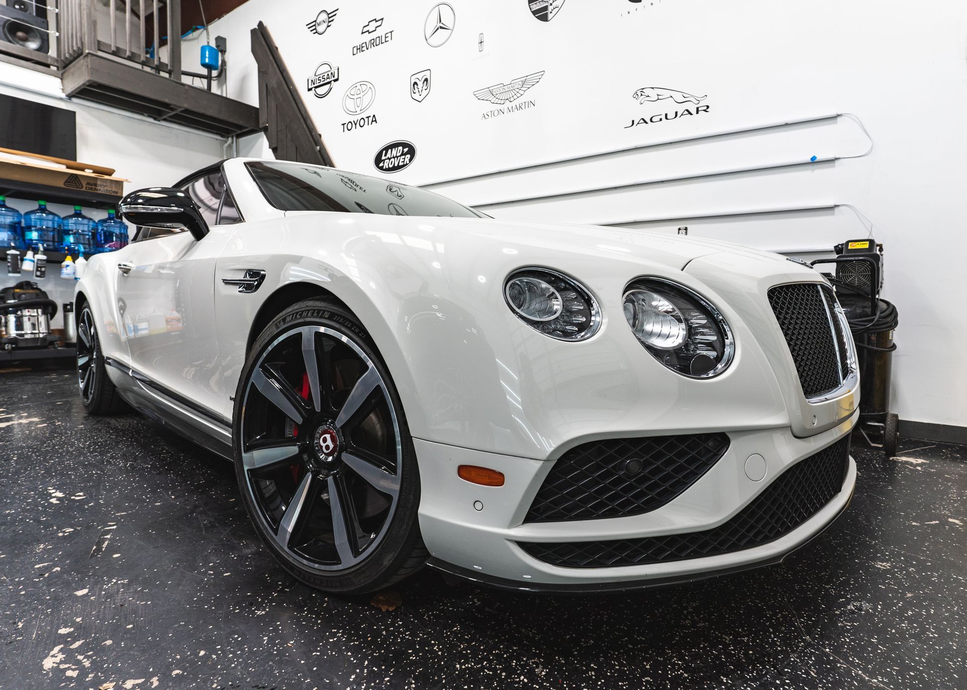 A white bentley is parked in a garage.