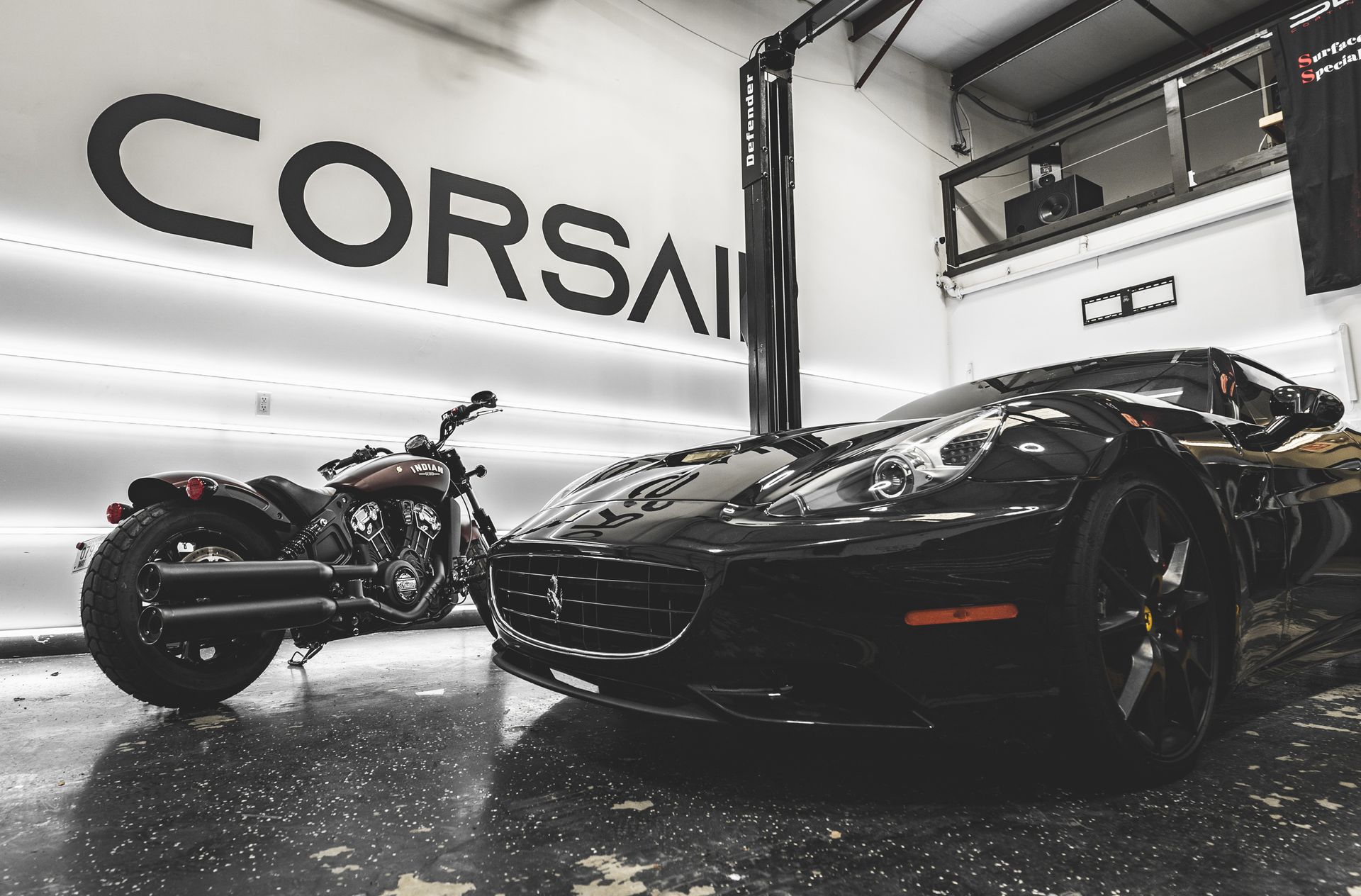 A car and motorcycle are parked in a garage with the word corsai on the wall