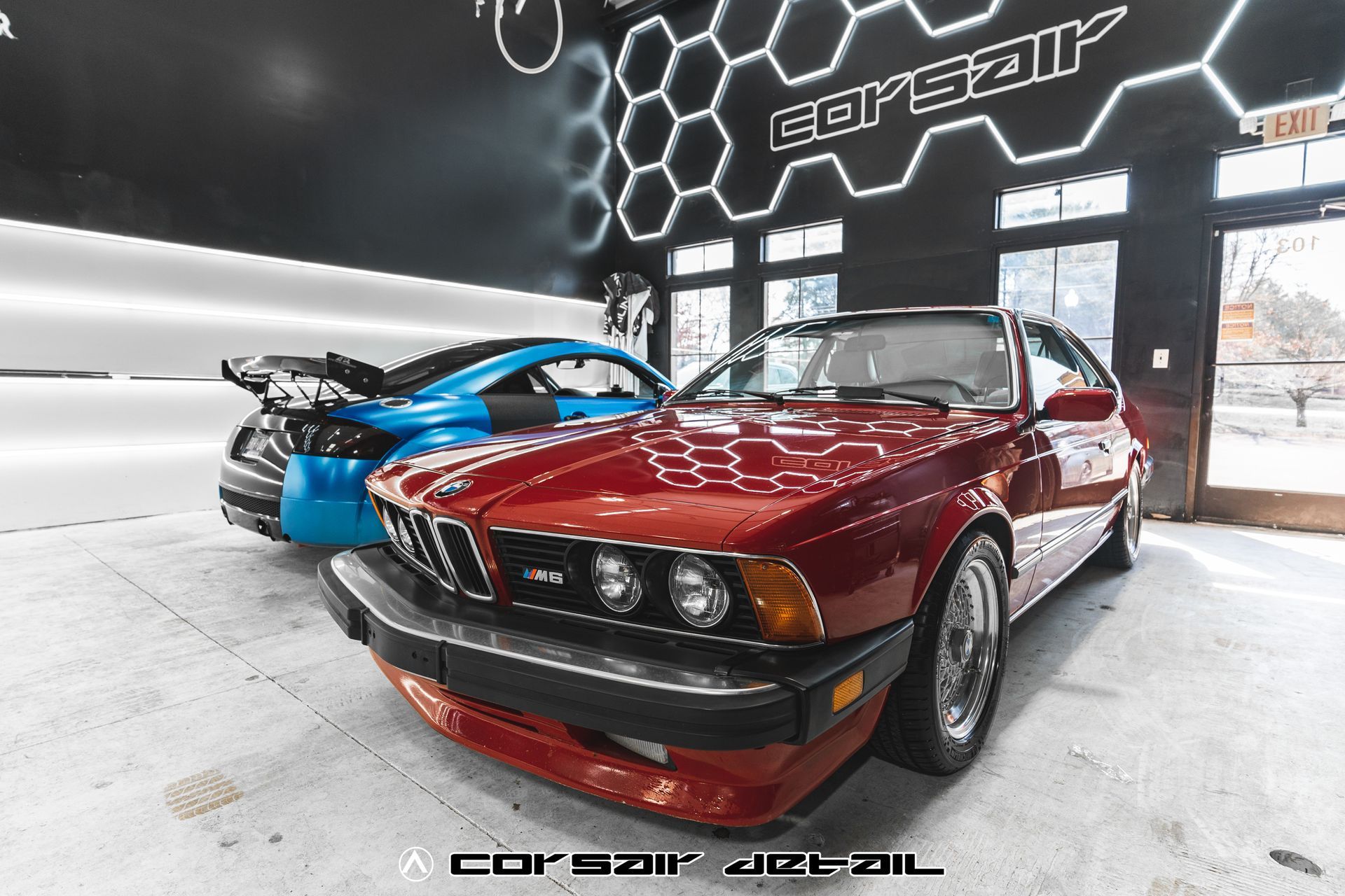 A red car is parked next to a blue car in a garage.